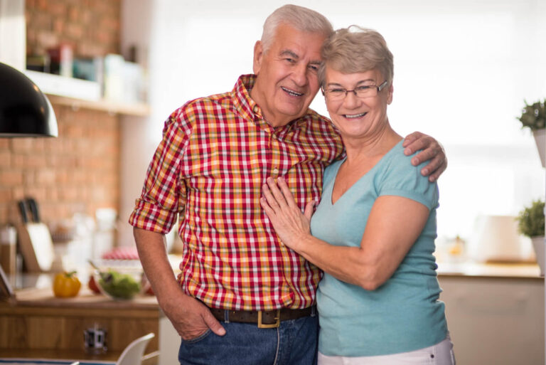 Casal de idosos sorridentes abraçados, representando a segurança nos implantes dentários para diabéticos na Odonto Caprio, no Brooklin.