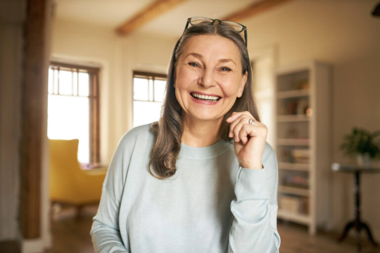 Mulher madura sorrindo alegremente com dentes alinhados após tratamento com prótese overdenture no Brooklin.