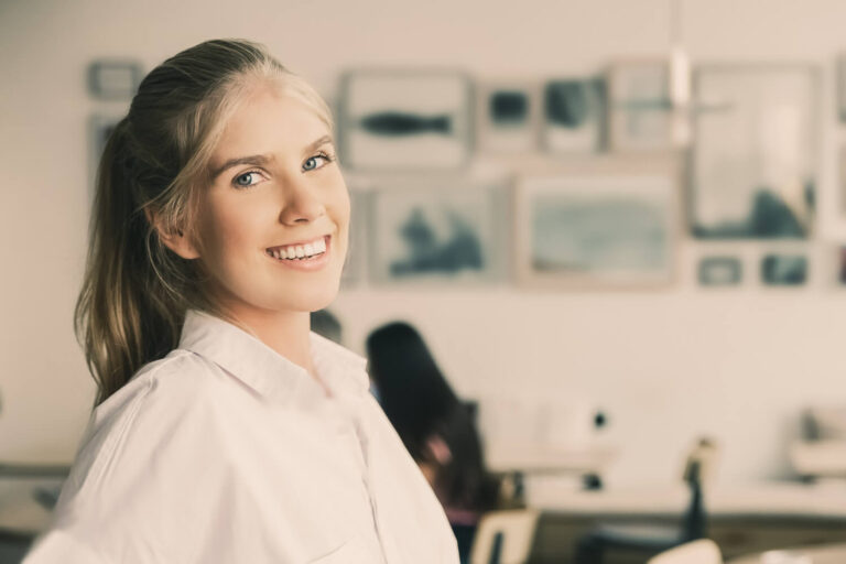Mulher loira sorrindo satisfeita exibindo dentes saudáveis após tratamento de implante dentário na Odonto Caprio no Brooklin.